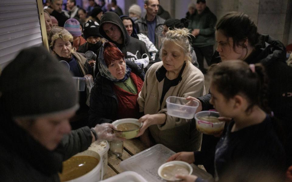 People who are sheltering in a metro station in northern Kharkiv receive food from volunteers - REUTERS/Thomas Peter