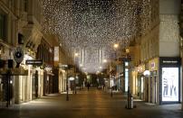 FILE - In this Monday, Nov. 23, 2020 file photo, the traditional Christmas lights shine over closed shops in downtown Vienna, Austria. Nations are struggling to reconcile cold medical advice with a holiday tradition that calls for big gatherings in often poorly ventilated rooms, where people chat, shout and sing together, providing an ideal conduit for a virus that has killed over 350,000 people in Europe so far. (AP Photo/Ronald Zak, File)