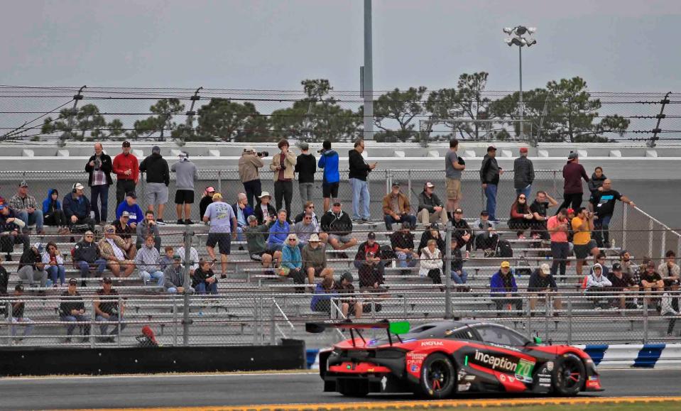 Cars speed through the infield course as fans watch from the bleachers.