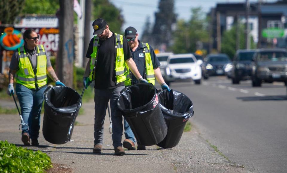 Tidy-Up Tacoma team members Angilia Smith (from left), Isaac Williams and Justin MacFarlane pick up trash along Pacific Avenue in Tacoma on Tuesday, May 14, 2024.