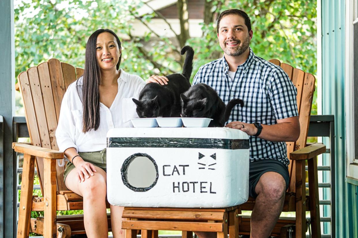 Kia Xiong and Tyler Donnelly are photographed with two feral cats, Chadwick and Pip, who will get to take advantage of the Cat Hotels created by the couple on Wednesday, July 19, 2023, in the Bates-Hendricks neighborhood of Indianapolis.