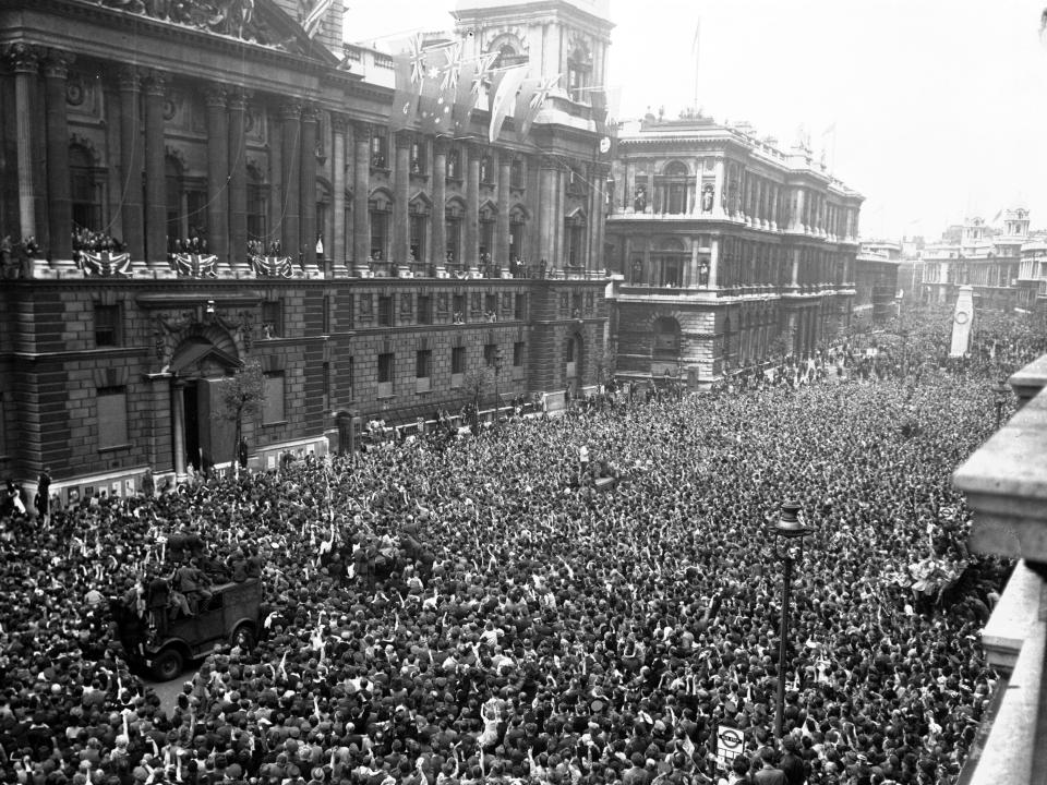 FILE - In this May 8, 1945 file photo crowds of civilians, British and Allied troops wave and cheer as Winston Churchill, second balcony from left, and members of the cabinet appear, to celebrate the end of the war in Europe, in Whitehall, London. Nazi commanders signed their surrender to Allied forces in a French schoolhouse 75 years ago this week, ending World War II in Europe and the Holocaust. Unlike the mass street celebrations that greeted this momentous news in 1945, surviving veterans are marking V-E Day this year in virus confinement, sharing memories with loved ones, instead of in the company of comrades on public parade. (AP Photo, File)