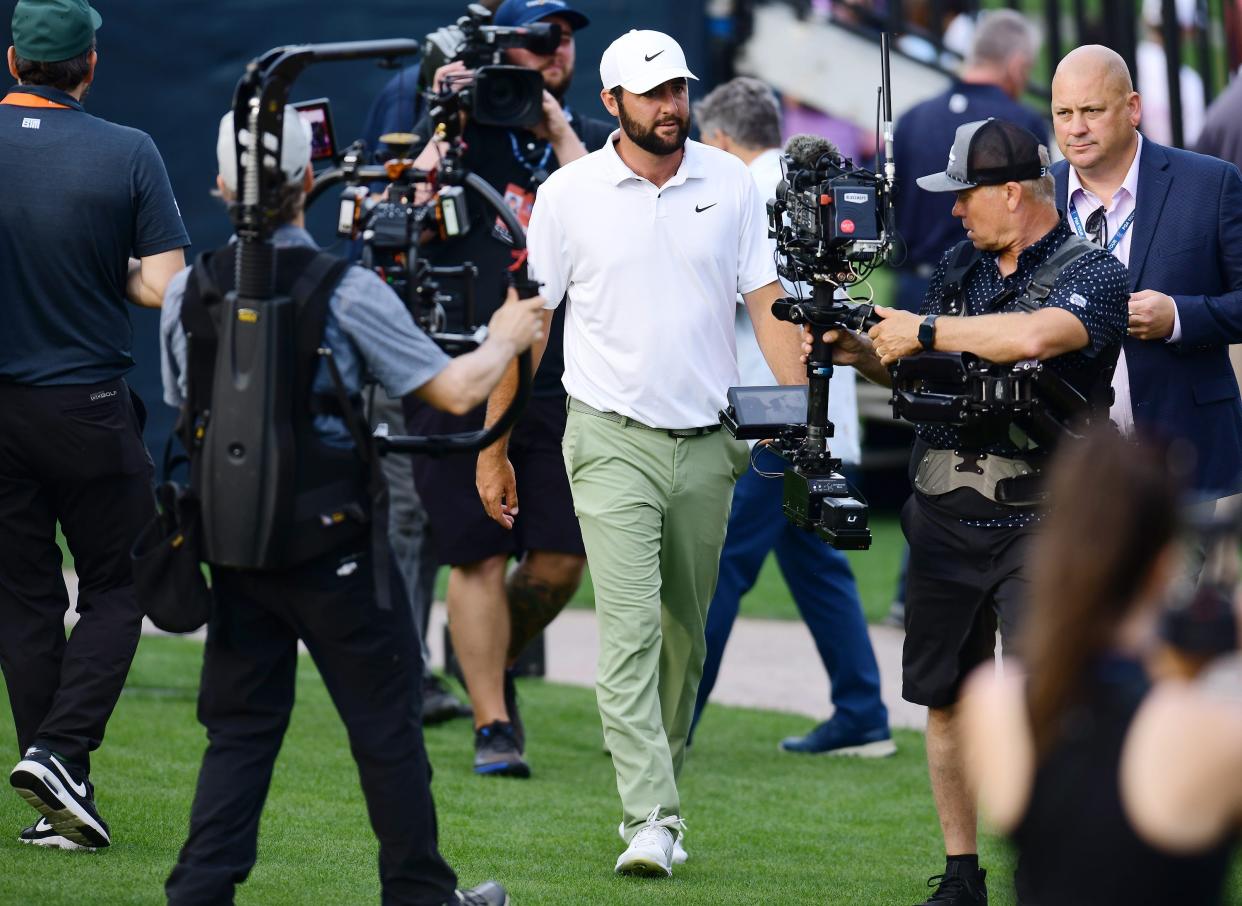 Scottie Scheffler is surrounded by cameras as he makes his way to the trophy presentation after winning the Players Championship tournament Sunday at TPC Sawgrass in Ponte Vedra Beach, Fla.