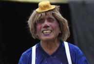 Circus clown Santos Chiroque, whose performance name is "Piojito," or Little Tick, laughs at his grandchild's comment that he looks like a woman, as he shows off his clown costume outside his home on the outskirts of Lima, Peru, Monday, Aug. 10, 2020. Chiroque's family used to run their own small circus, but since March when the lockdown to curb COVID-19 closed their business, and the requirement for people over 60 to self-quarantine kept the 74-year-old at home, they started selling circus food like caramelized apples to survive. (AP Photo/Martin Mejia)