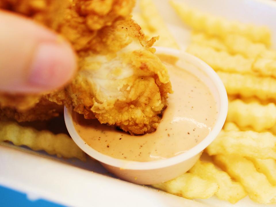 raising canes chicken tender dipped in canes sauce