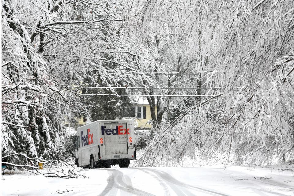 A delivery truck weaves around sagging and fallen branches on Greystone Drive in Holden Monday.