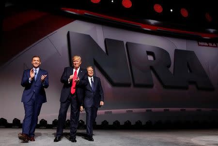 NRA Executive Director Chris Cox (L) and Executive Vice President and CEO Wayne LaPierre (R) welcome U.S. President Donald Trump (C) onstage to deliver remarks at the National Rifle Association (NRA) Leadership Forum at the Georgia World Congress Center in Atlanta, Georgia, U.S., April 28, 2017. REUTERS/Jonathan Ernst