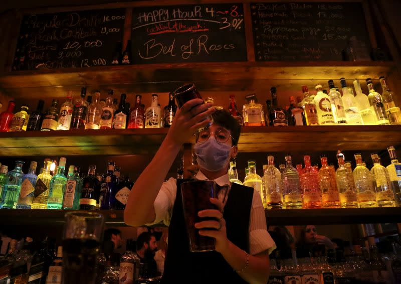 FILE PHOTO: A female bartender wearing a protective face mask mixes an alcoholic drink at a bar, in Beirut