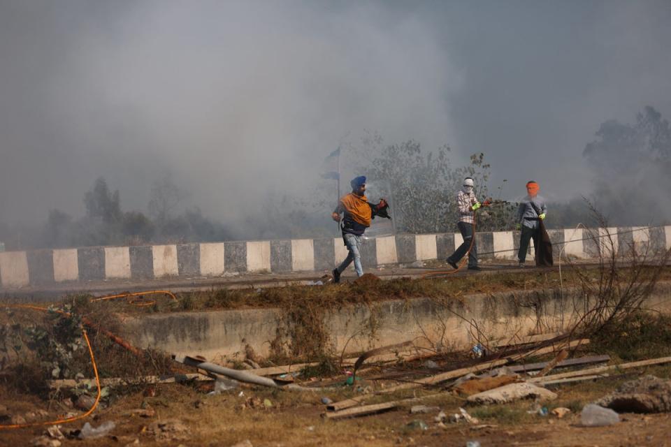 People stand amidst tear gas fired by police to disperse farmers who are marching towards New Delhi (REUTERS)