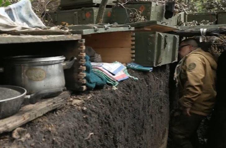 Senior Lieutenant Taras Berezovets, of Ukraine's Bohun Special Forces Brigade, looks at items abandoned by Russian soldiers in a trench as they fled a front-line position in the Kharkiv region in September 2022. / Credit: CBS News