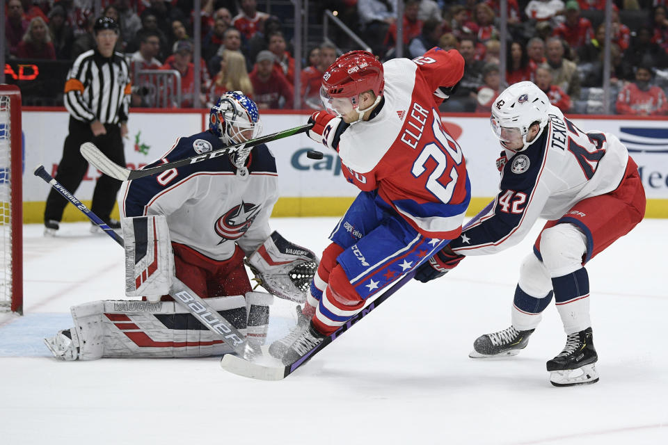 Columbus Blue Jackets goaltender Joonas Korpisalo (70) watches the puck next to Washington Capitals center Lars Eller (20), of Denmark, during the first period of an NHL hockey game, Monday, Dec. 9, 2019, in Washington. Also seen is Blue Jackets center Alexandre Texier (42). (AP Photo/Nick Wass)