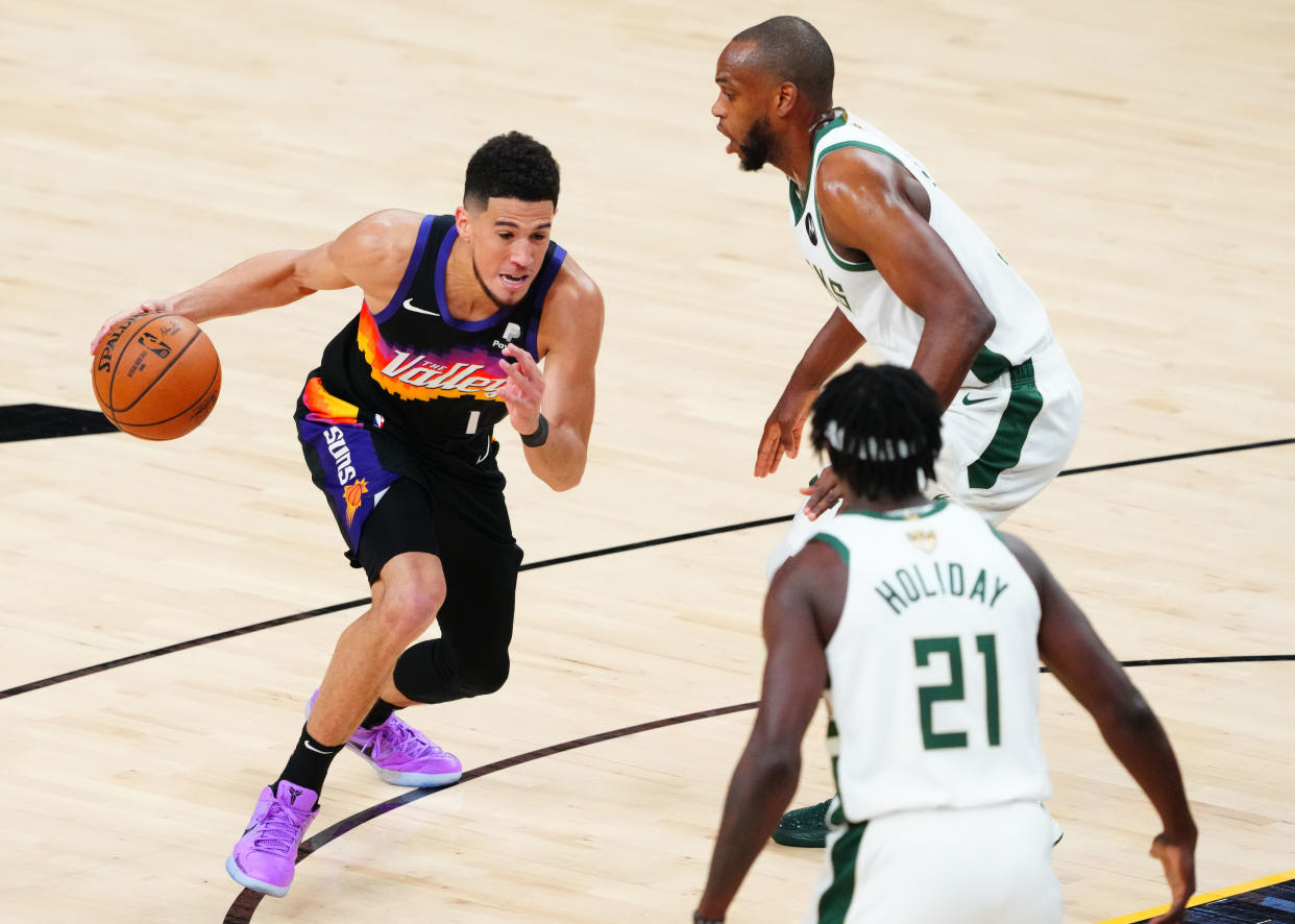 Suns star Devin Booker (left) is in for one awkward plane ride to Tokyo with the Bucks' Khris Middleton and Jrue Holiday, who just beat him in the NBA Finals. (Mark J. Rebilas-USA TODAY Sports)