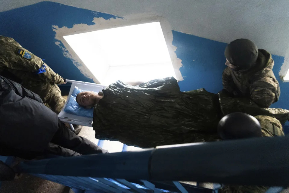 A Ukrainian serviceman and a civilian carry a wounded man who was injured by shelling in a hospital in Mariupol, Ukraine, Thursday, March 3, 2022. (AP Photo/Mstyslav Chernov)