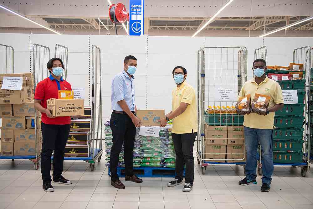 Tesco staff giving the Tabung Kiriman Ikhlas food items to Food Aid Foundation representatives for distribution. — Picture courtesy of Tesco Malaysia