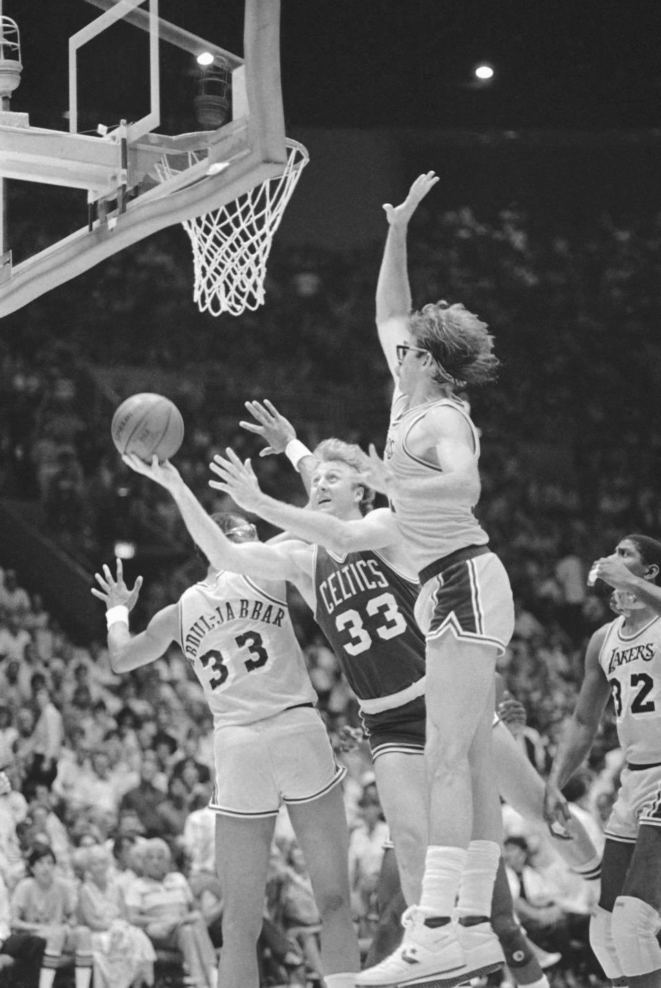 FILE - Boston Celtics forward Larry Bird (33) attempts a shot through defending Los Angeles Lakers forward Kurt Rambis (31), right and center Kareem Abdul Jabbar during NBA Championship series match on June 8, 1985, at the Forum in Inglewood, Calif. (AP Photo/Lennox McLendon)