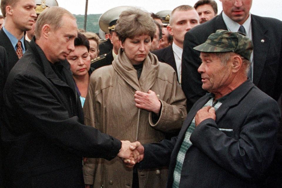 FILE - Russian President Vladimir Putin shakes hands with an unidentified relative of a seaman, who is believed dead aboard the crippled nuclear submarine Kursk as Lyudmila Lyachin, wife of Grigory Lyachin, the captain of the sunken submarine Kursk is seen center, in the closed military base of Vedyayevo, 50 miles (80 kms) north from Murmansk on Aug. 22, 2000. The Kursk submarine sinks with 118 people aboard, setting off the first widespread and sustained criticism of Putin, who remained on vacation early in the crisis and waited five days before accepting Western offers of help. (Pool Photo via AP, File)