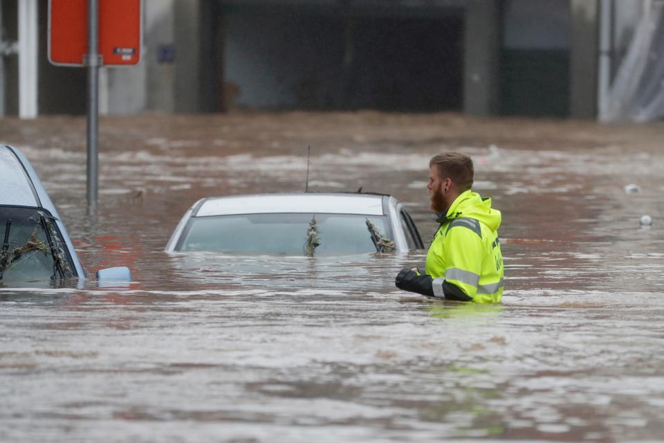 A man wades through the water to reach cars submerged by the heavy rains in Ensival (EPA)