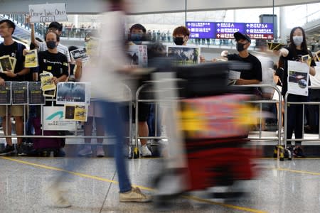 Anti-extradition bill protesters hold up placards for arriving travellers during a protest at the arrival hall of Hong Kong International Airport in Hong Kong