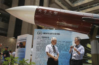 FILE - In this Aug. 13, 2015, file photo, two men speak under the Taiwan-made "Tien-Kung III" surface to air missile during the 2015 Taipei Aerospace and Defense Technology Exhibition in Taipei, Taiwan. Taiwan is responding to China’s defense buildup by developing missiles and interceptors of its own that could reduce Beijing’s military advantage over the island, defense experts say. (AP Photo/Wally Santana, File)