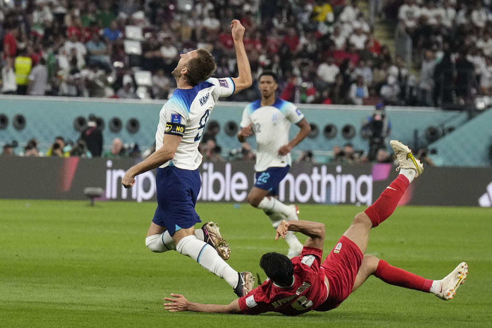 El capitán inglés Harry Kane (izquierda) recibe una falta del iraní Morteza Pouraliganji en el partido por el Grupo B del Mundial en Doha, Qatar, el lunes 21 de noviembre de 2022. (AP Foto/Martin Meissner)