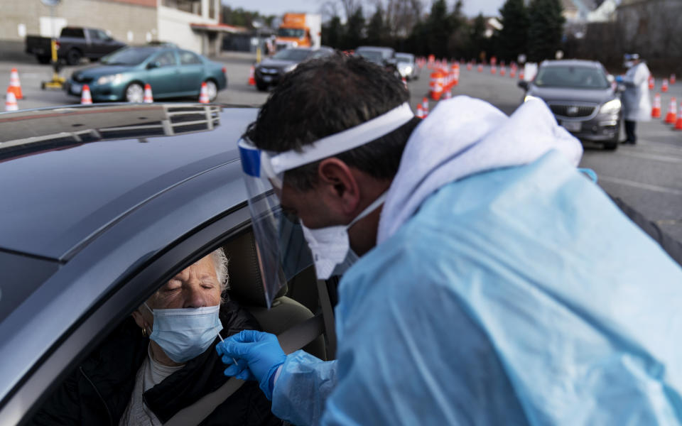 FILE - In this Dec. 9, 2020, file photo, Beverly Palazzi is swabbed for COVID-19 by Milton Giard at a testing site set up outside McCoy Stadium in Pawtucket, R.I. After a punishing fall that left hospital struggling, some Midwestern states are seeing a decline in new coronavirus cases. But the signs of improvement are offset by the infection’s accelerating spread on both coasts. (AP Photo/David Goldman, File)
