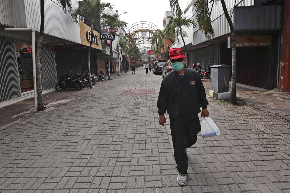 In this Thursday, April 30, 2020, photo, a man walks past rows of shops closed due to the new coronavirus outbreak at Pasar Baru Shopping Center that is popular for its textiles products in Jakarta, Indonesia. May Day usually brings both protest rallies and celebrations rallies marking international Labor Day. This year it's a bitter reminder of how much has been lost for the millions left idle or thrown out of work due to the coronavirus pandemic. Garment workers in Asia are among the hardest hit as orders dry up and shutdowns leave factories shuttered. (AP Photo/Tatan Syuflana)