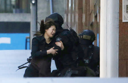 A hostage runs towards a police officer outside Lindt cafe, where other hostages are being held, in Martin Place in central Sydney December 15, 2014. REUTERS/Jason Reed