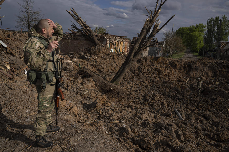 A Ukrainian serviceman inspects a site after an airstrike by Russian forces in Bahmut, Ukraine, Tuesday, May 10, 2022. (AP Photo/Evgeniy Maloletka)