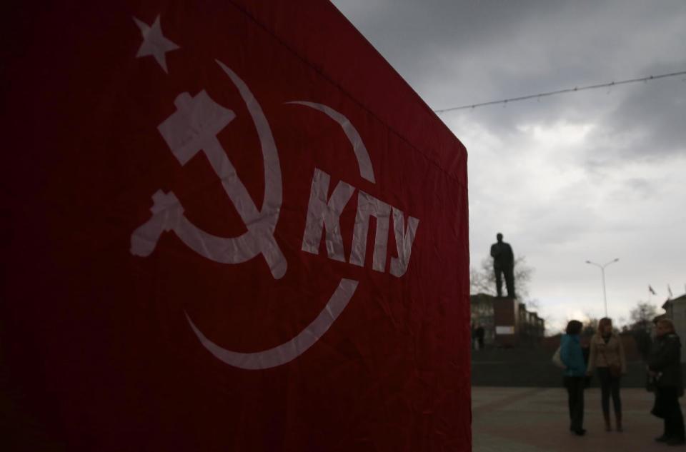 In this photo taken Wednesday, March 5, 2014, a tent with symbolics and name of Ukrainian Communists party seen as people discuss the situation at a central square in Simferopol, Ukraine. Ukraine is facing a potentially crippling geographic and cultural divide, a growing gulf between supporters of Russia who dominate the east and south of the country, and western Ukrainians who yearn for closer ties to Western Europe. One side of that divide is even starker in Crimea, a Black Sea peninsula. For much of the past 200 years, Crimea was under Russian and Soviet control, and today most Crimeans see themselves as only nominally Ukrainian and Russian is, by far, the dominant language (AP Photo/Sergei Grits)