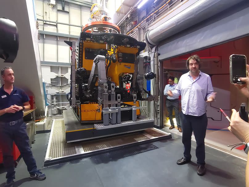 Mark Dalio (R) talks journalists through OceanX's unique approach beside the ROV.