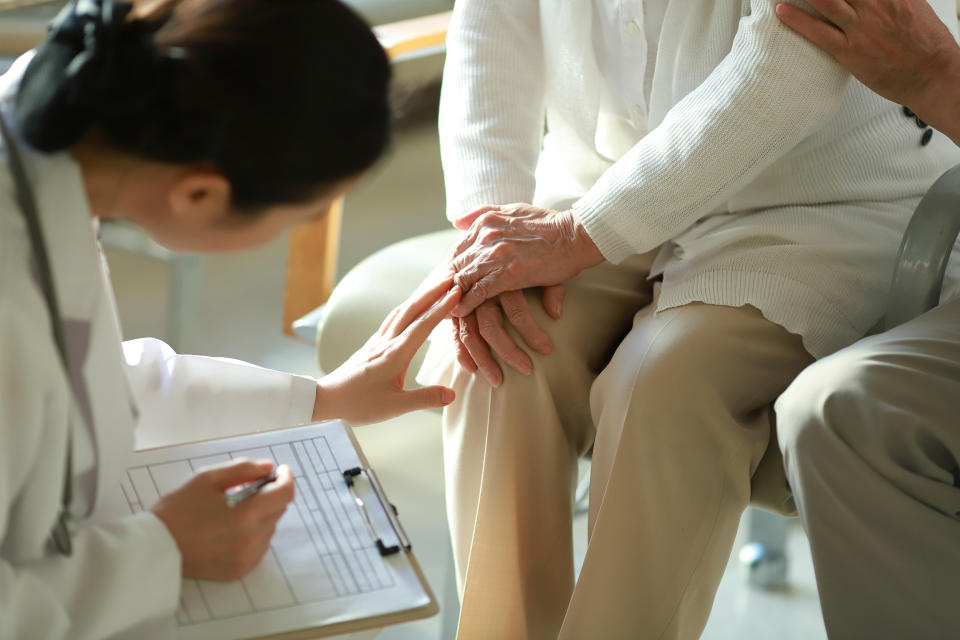 Doctor checking patient's knee pain (RUNSTUDIO / Getty Images)