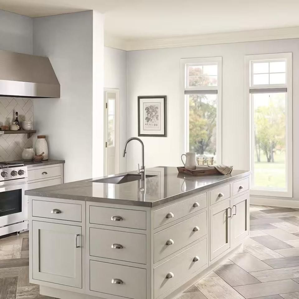 A hyper-realistic 3D render of a bright modern kitchen (with a large kitchen island) painted in White Veil by Behr. 