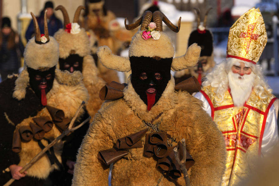 Revelers take part in a traditional St. Nicholas procession in the village of Lidecko, Czech Republic, Monday, Dec. 4, 2023. This pre-Christmas tradition has survived for centuries in a few villages in the eastern part of the country. The whole group parades through the village for the weekend, going from door to door. St. Nicholas presents the kids with sweets. The devils wear home-made masks of sheep skin and the white creatures representing death with scythes frighten them. (AP Photo/Petr David Josek)