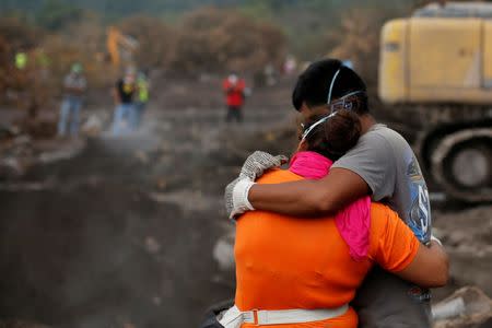Eva Ascon, is embraced by a family member as rescue workers search for her rest of her family at the affected by the Fuego volcano at San Miguel Los Lotes in Escuintla, Guatemala June 15, 2018. REUTERS/Carlos Jasso/Files