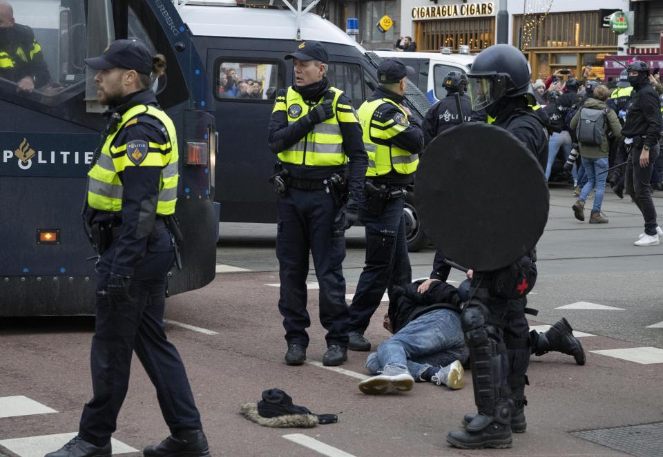 Police arrest a demonstrator as thousands of people defied a ban Sunday to gather and protest the Dutch government's coronavirus lockdown measures, in Amsterdam, Netherlands, Sunday, Jan. 2, 2022. The municipality of the Dutch capital banned the protest, saying police had indications some demonstrators could be attending "prepared for violence." (AP Photo/Peter Dejong)