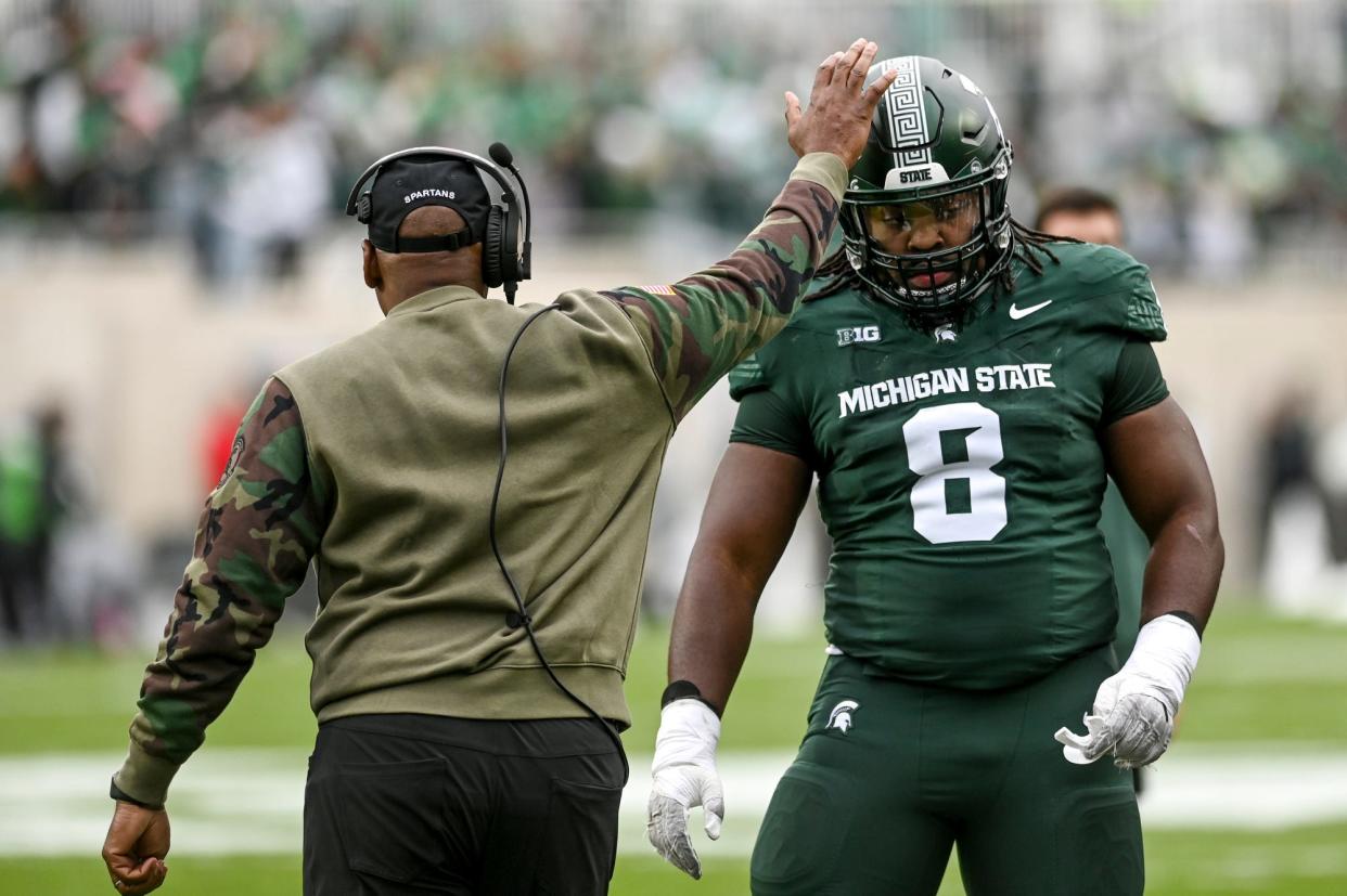 Michigan State's interim head coach Harlon Barnett, left, pats Simeon Barrow Jr. on the helmet during the first quarter in the game against Nebraska on Saturday, Nov. 4, 2023, at Spartan Stadium in East Lansing.