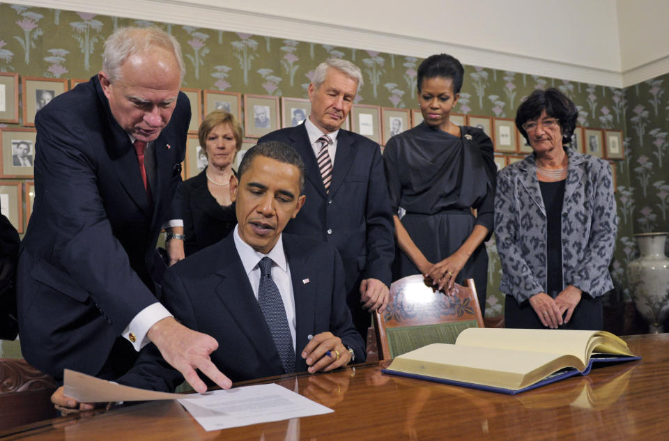 FILE - US President Barack Obama talks with Nobel Institute Executive Director Geir Lundestad, left, as first lady Michelle Obama, second from right, and others look on during a Nobel Signing Ceremony at the Nobel Institute in Oslo, Norway, Thursday, Dec. 10, 2009. In a break with Nobel tradition, the former secretary of the Nobel Peace Prize committee, Lundestad, said that the 2009 award to President Barack Obama failed to live up to the panel’s expectations. Lundestad wrote in a 2015 book that the committee had expected the prize to deliver a boost to Obama. Instead the award was met with fierce criticism in the U.S., where many argued Obama had not been president long enough to have an impact worthy of the Nobel. (AP Photo/Susan Walsh, File)