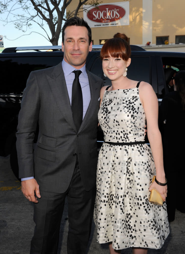 Man in a gray suit and woman in a white dress with black spots, both smiling, standing side by side