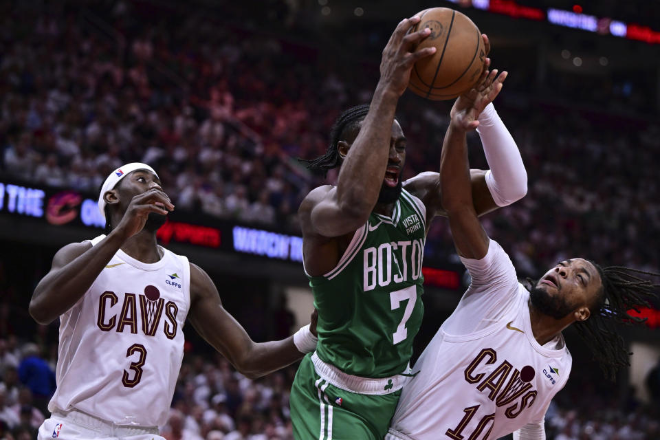 Boston Celtics guard Jaylen Brown (7) goes to the basket against Cleveland Cavaliers guards Darius Garland, right, and Caris LeVert (3) during the second half of Game 4 of an NBA basketball second-round playoff series, Monday, May 13, 2024, in Cleveland. (AP Photo/David Dermer)