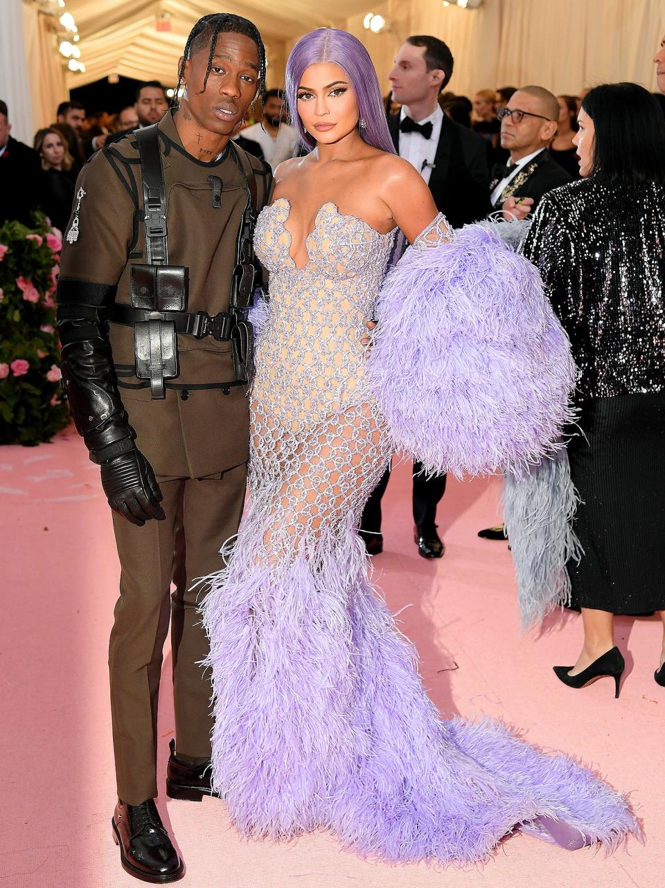 Travis and Kylie definitely got the <a href="https://people.com/style/met-gala-2019-kendall-jenner-kylie-jenner-red-carpet/" rel="nofollow noopener" target="_blank" data-ylk="slk:2019 Met Gala;elm:context_link;itc:0;sec:content-canvas" class="link ">2019 Met Gala</a> camp memo when they arrived in stunning, on-theme looks. The rapper wore a double-breasted suit by Kim Jones for Dior and the reality star wore a sheer Versace dress.