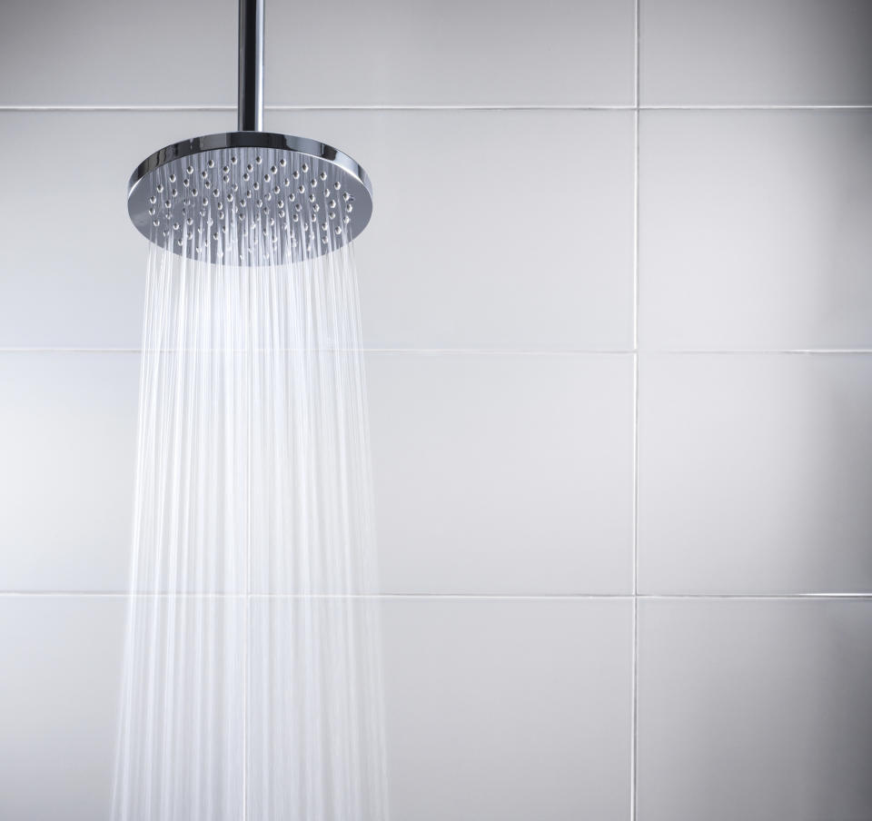 A shot of a shower head with streaming water coming out of it