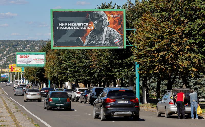 Vehicles drive past advertising boards in Luhansk