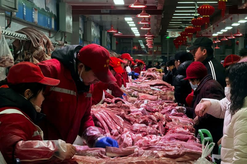 FILE PHOTO: Pork sellers attend to customers at a market in Beijing