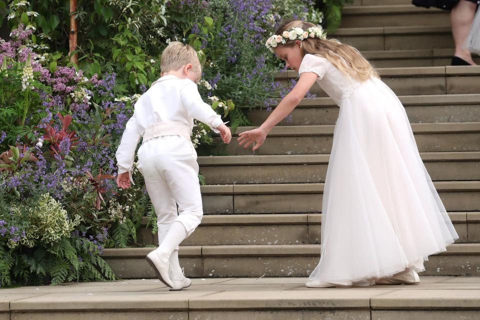 A page boy and bridesmaid walk up the chapel stairs