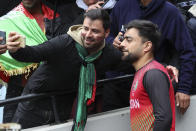 Afghanistan's Rashid Khan, right, poses for a selfie with a fan as play was abandoned due to rain in the T20 World Cup cricket match between Afghanistan and Ireland in Melbourne, Australia, Friday, Oct. 28, 2022. (AP Photo/Asanka Brendon Ratnayake)