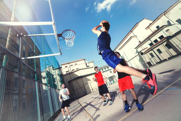 A player takes a shot during an outdoor basketball game.