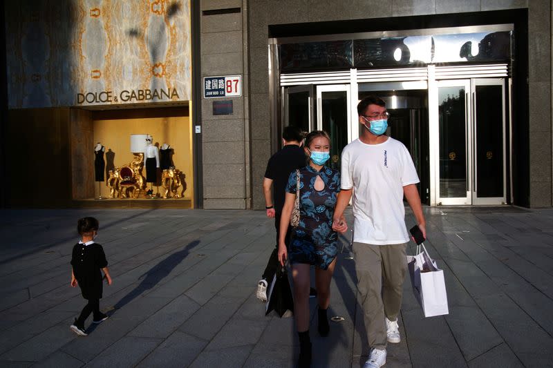 People wearing face masks following the COVID-19 outbreak walk out of a shopping mall in Beijing