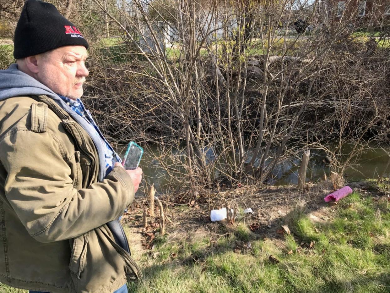 Bryon Frady of Melvindale, whose hobby is cleaning litter and other debris from rivers, views a spot beside Ecorse Creek in Lincoln Park where litter is scattered around saplings gnawed off by a beaver, during a survey of debris in and near the creek on April 8, 2024.