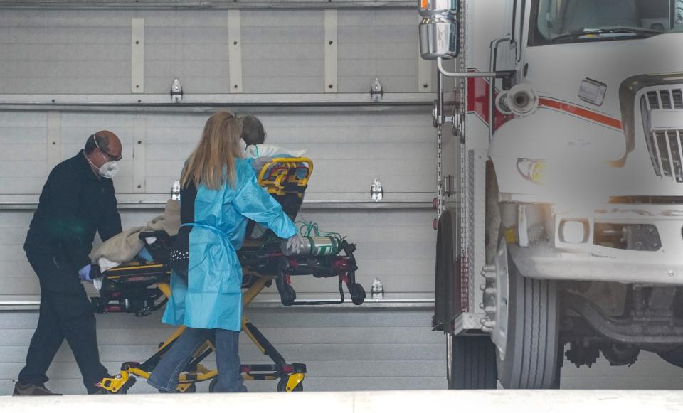 EMTs Ericka Nicholson and Roy Litfin wheel a COVID-19 positive patient into their waiting ambulance for transport for a larger hospital from Quinter, Kansas.