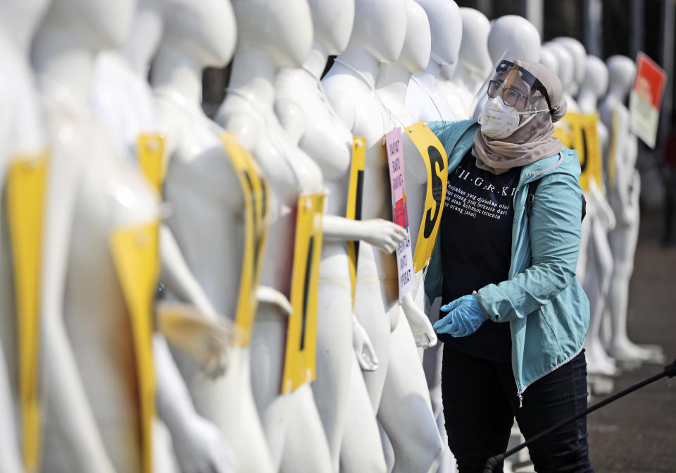 A Greenpeace activists wearing protective gear to help curb the spread of the coronavirus arranges mannequins used to display posters during a protest outside the parliament in Jakarta, Indonesia, Monday, June 29, 2020. About a dozen of activists staged the protest against the government's omnibus bill on job creation that was intended to boost economic growth and create jobs, saying that it undermined labor rights and environmental protection. (AP Photo/Dita Alangkara)